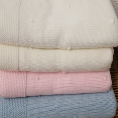 Quatro mantas de malha em branco, creme, rosa e azul claro empilhadas