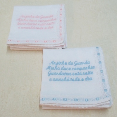 Dois panos de burro brancos bordados em azul e rosa com texto e bordas decorativas