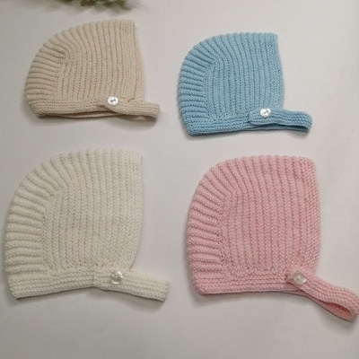 Quatro gorros tricotados em várias cores com botões decorativos brancos com brilhantes.