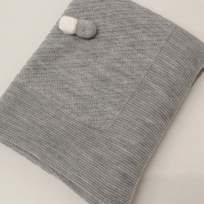 Cobertor cinzento de malha com três pompons decorativos