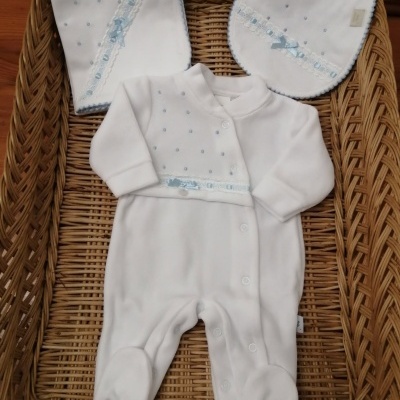Conjunto de bebé branco com detalhes azuis numa cesta de verga