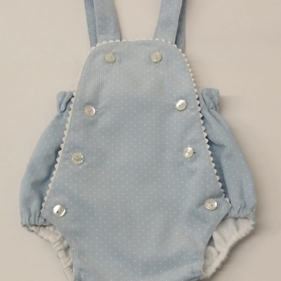 Macacão azul claro para bebê com botões brancos e pontos pequenos brancos.