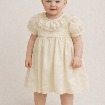 Bebé com vestido creme de renda e sapatinhos com pérolas e laços