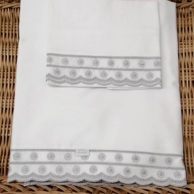 Conjunto de toalha branca com bordado cinza e superfície de vime