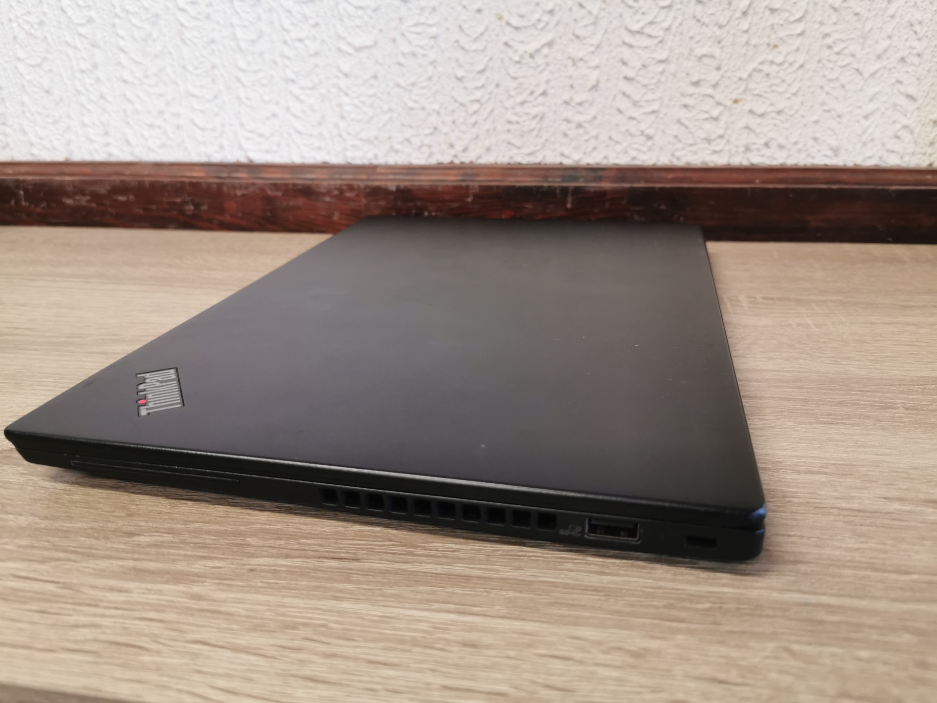 LENOVO ThinkPad X395 Portátil preto ThinkPad fechado sobre superfície de madeira clara