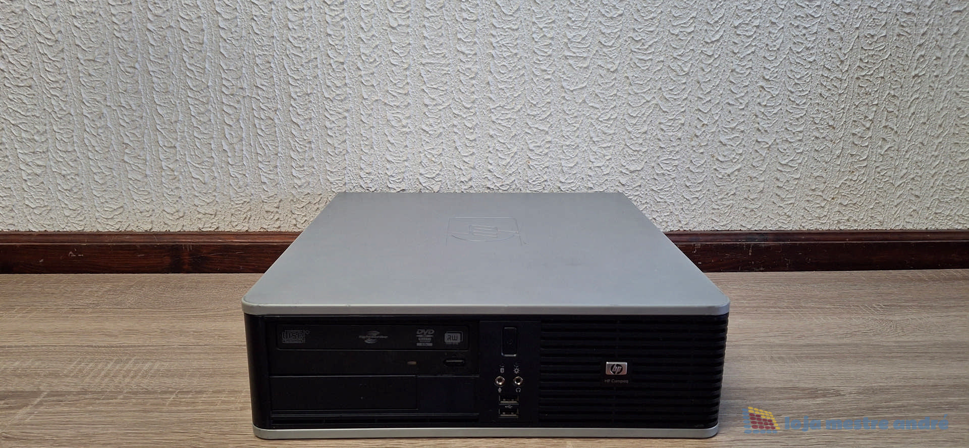 Computador desktop HP Compaq DC7900 Intel Core 2 Duo SSD 120GB HDD 500GB Windows 10 Home Computador de secretária preto e cinza da marca HP em chão de madeira junto a parede branca