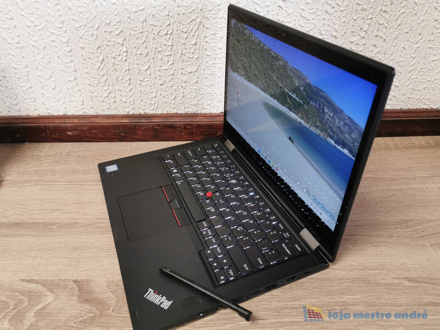 Computador portátil LENOVO Thinkpad X380 Yoga Touch-Screen IPS Full HD Intel Core i5 SSD 256GB Windows 11 PRO Computador portátil Lenovo ThinkPad aberto com ecrã a mostrar uma praia, colocado no chão de madeira junto a parede branca