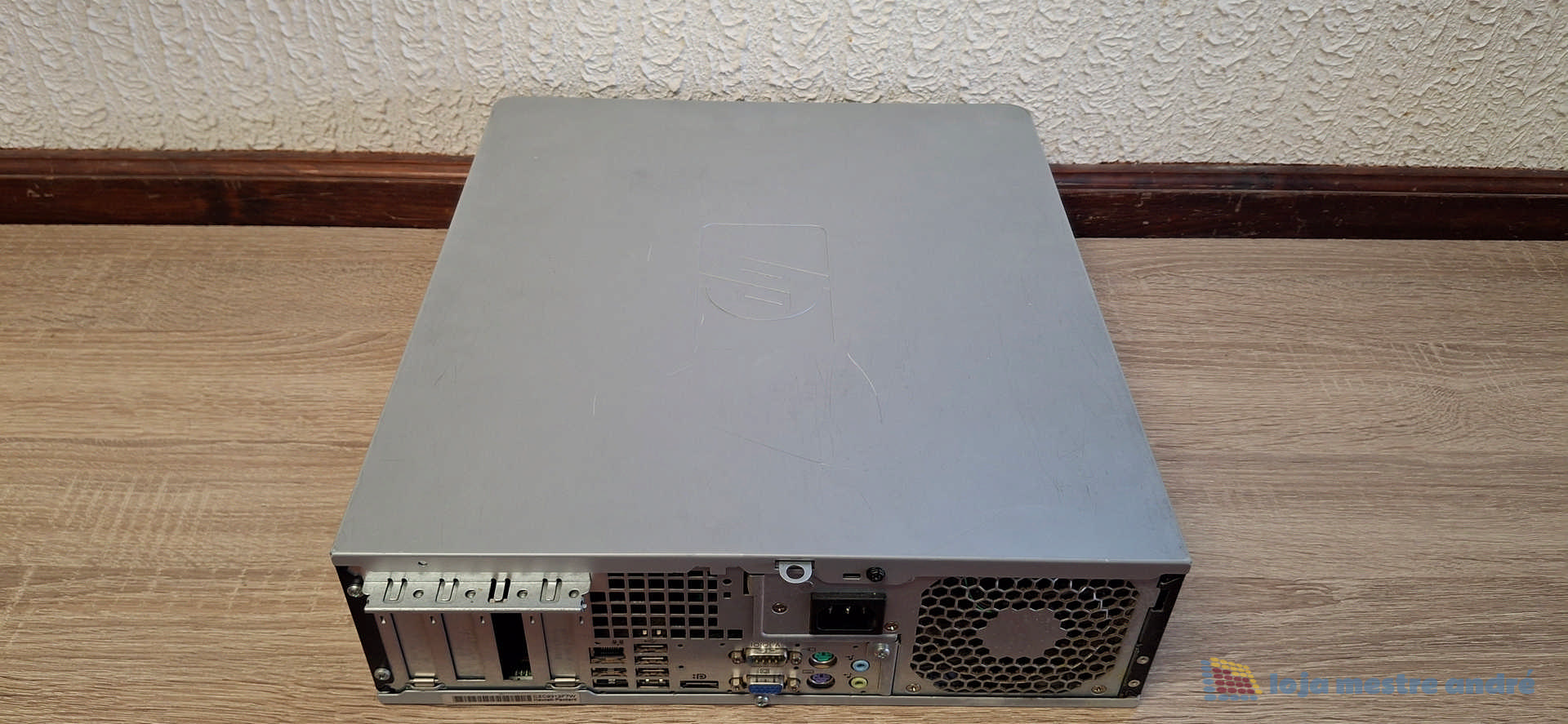 Computador desktop HP Compaq DC7900 Intel Core 2 Duo SSD 120GB HDD 500GB Windows 10 Home Computador de secretária cinza visto pela parte traseira num chão de madeira.