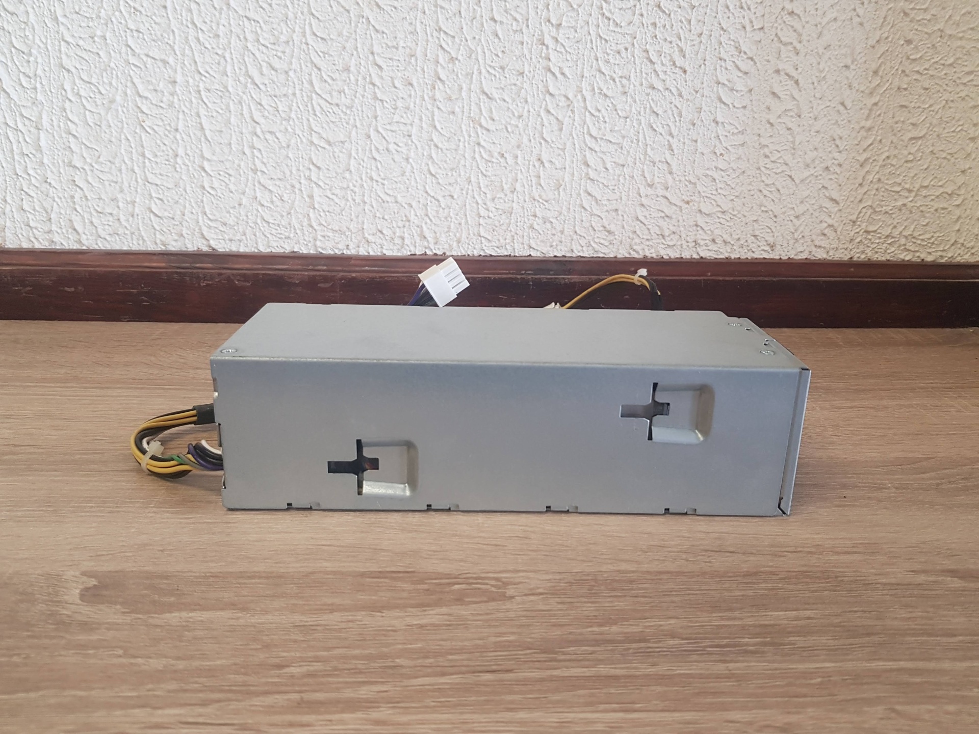 Fonte de Alimentação DELL 240w Fonte de alimentação de metal cinzento com cabos numa superfície de madeira