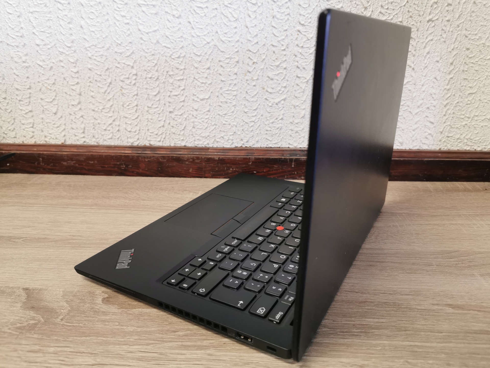LENOVO ThinkPad X395 Computador portátil preto ThinkPad parcialmente aberto sobre mesa de madeira