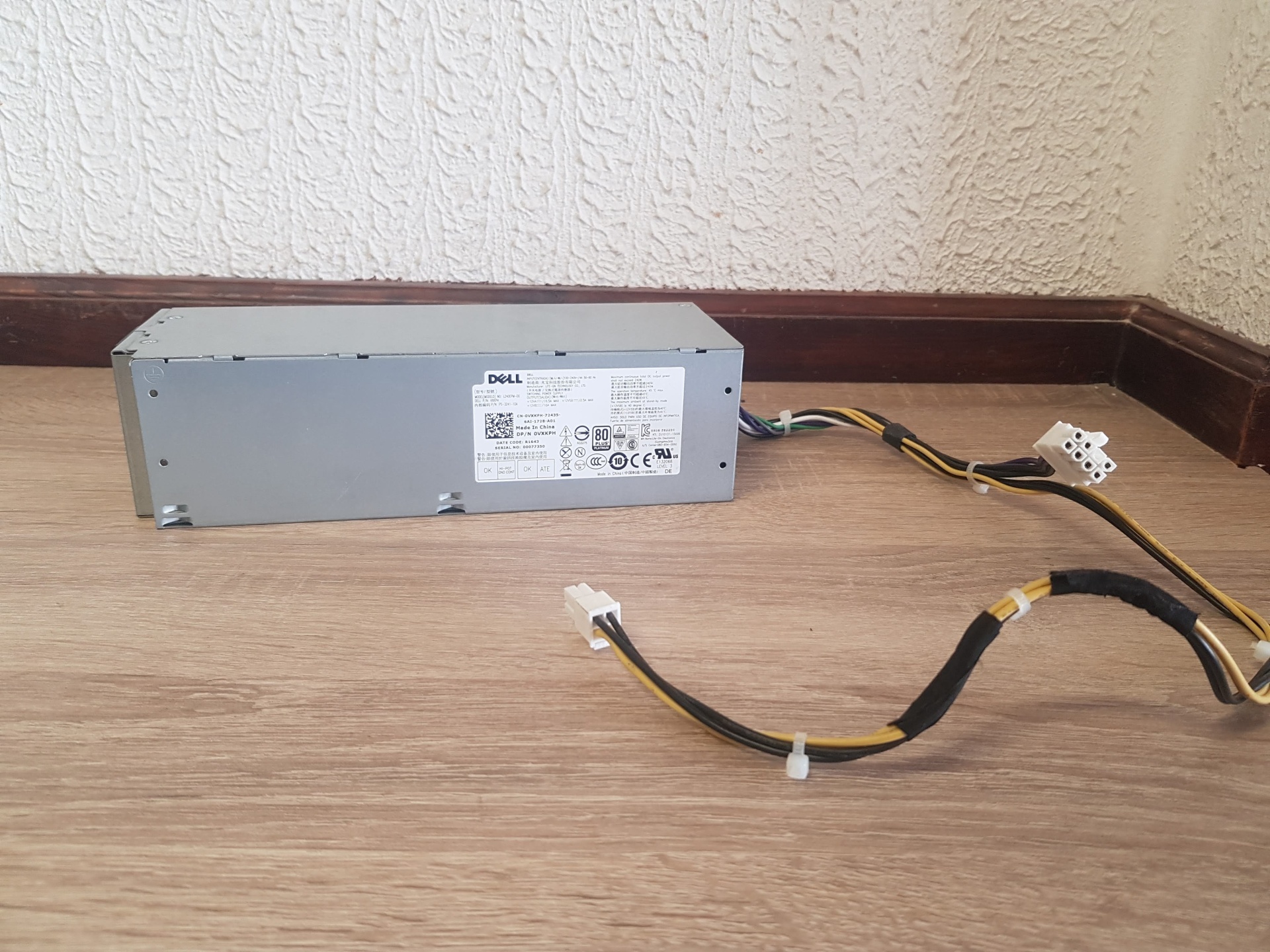 Fonte de Alimentação DELL 240w Fonte de alimentação Dell cinza com cabos pretos sobre chão de madeira