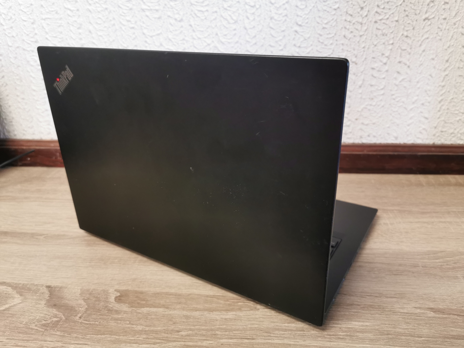 LENOVO ThinkPad X395 Portátil preto ThinkPad parcialmente aberto em superfície de madeira