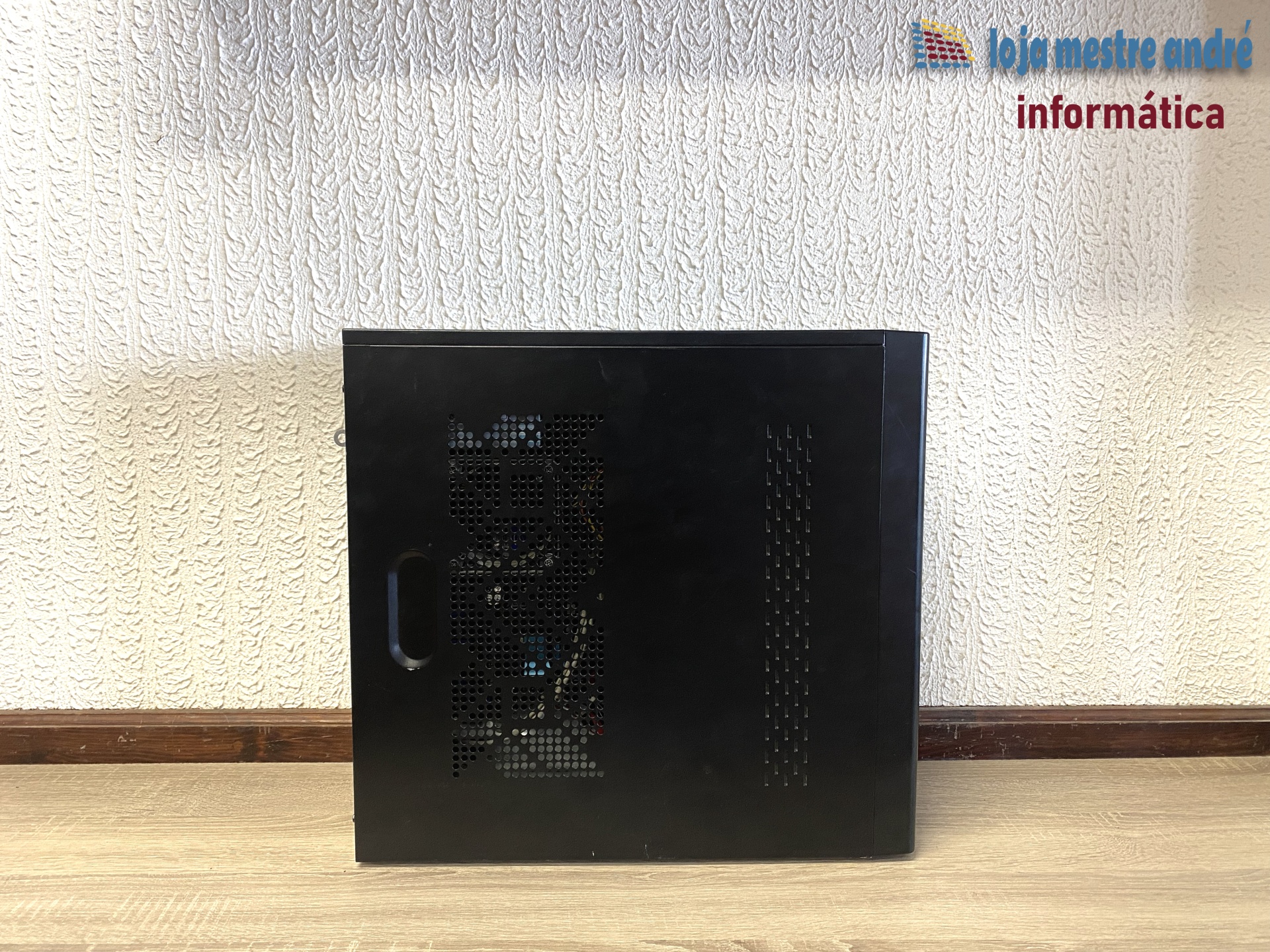 LMA B2 Computador desktop preto com ventoinhas visíveis lateralmente sobre chão de madeira