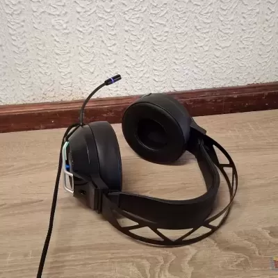 Headset preto com almofadas em tecido sobre piso de madeira clara