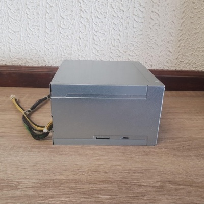 Fonte de alimentação para computador cinza com cabos elétricos sobre chão de madeira