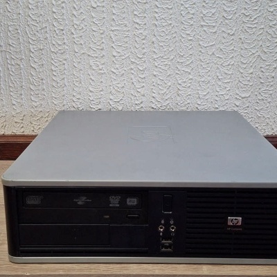 Computador de secretária HP preto e cinza sobre mesa de madeira