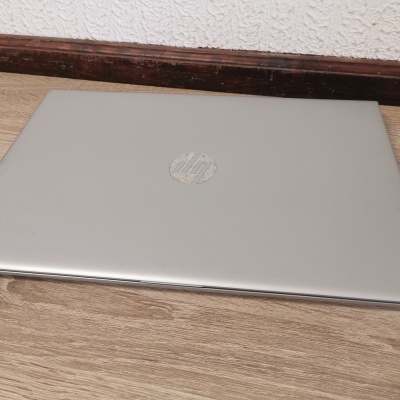 Computador portátil HP prateado fechado sobre uma mesa de madeira clara