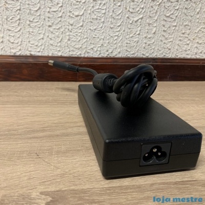 Adaptador de corrente preto com cabo enrolado sobre superfície de madeira