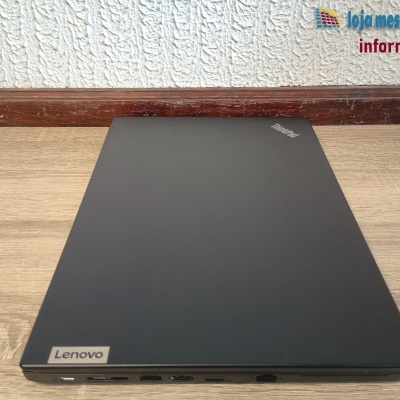 Computador portátil Lenovo preto fechado numa superfície de madeira com parede branca ao fundo e logo da loja mestre andré informática.