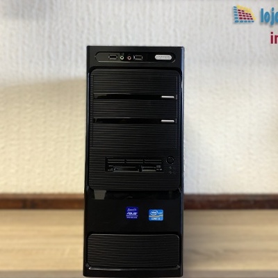 Torre de computador preta com etiquetas Intel e ASUS em fundo de parede clara e chão de madeira