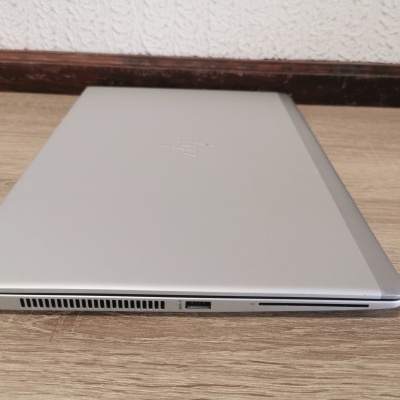 Portátil HP prateado fechado numa superfície de madeira clara