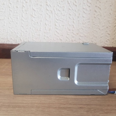 Computador portátil cinzento metálico com cabos coloridos sobre chão de madeira clara