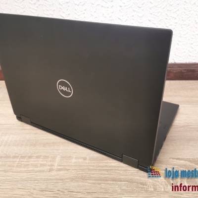 Computador portátil preto Dell inclinado numa superfície de madeira