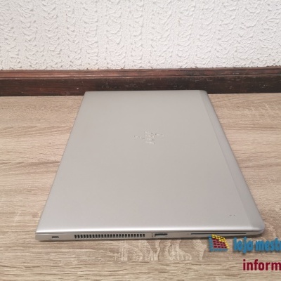 Computador portátil cinzento fechado com porta USB e ventoinha na lateral sobre superfície de madeira