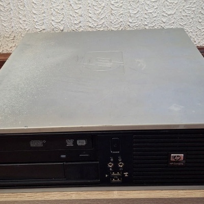 Computador de secretária HP cinzento e preto sobre chão de madeira