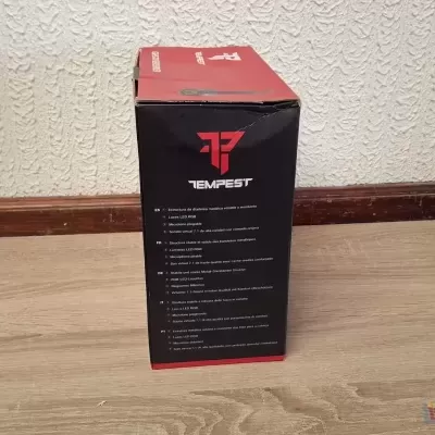 Embalagem preta e vermelha da TEAMFEST com texto informativo, em chão de madeira