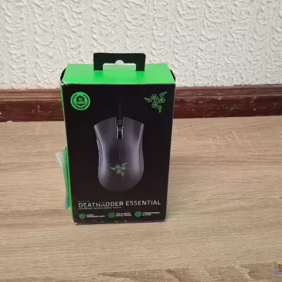 Caixa de rato gaming Razer DeathAdder Essential preta e verde sobre piso em madeira clara