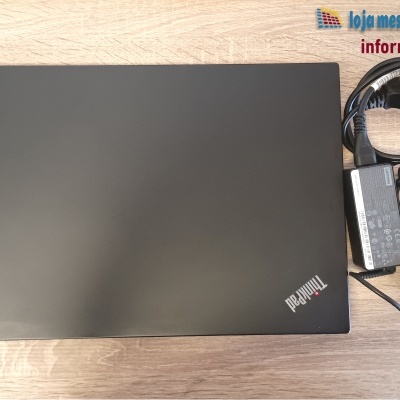 Computador portátil Lenovo ThinkPad preto fechado com carregador sobre mesa de madeira