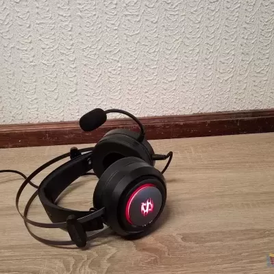 Headset gaming preto com microfone e luz vermelha no chão