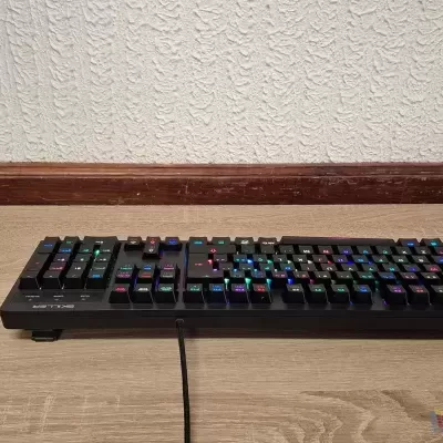 Teclado mecânico compacto preto iluminado em RGB numa superfície de madeira