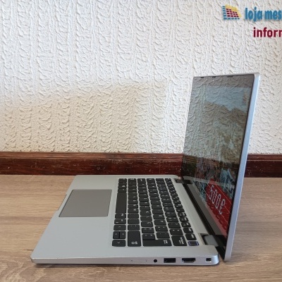 Computador portátil cinzento com teclado preto e ecrã aberto sobre mesa de madeira