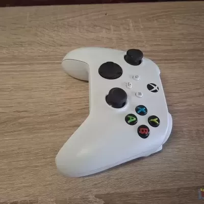 Comando de videojogo branco com botões coloridos sobre madeira clara