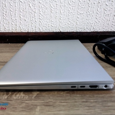 Portátil cinzento metálico com portas USB-C, HDMI e mini tomada, sobre mesa de madeira clara