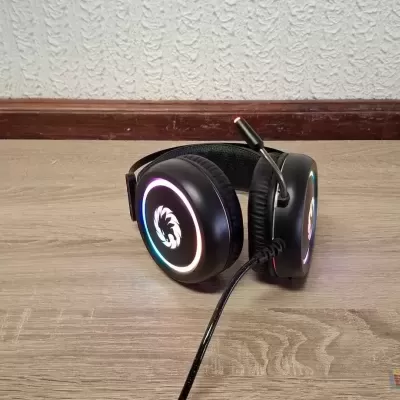Auriculares gaming pretos com luzes LED coloridas no chão de madeira clara