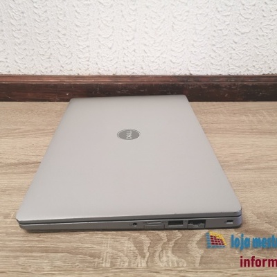 Computador portátil Dell fechado cinzento numa superfície de madeira clara