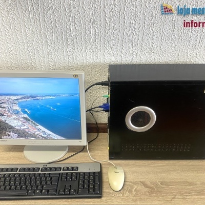 Computador desktop, monitor LCD, teclado HP, rato Fujitsu Siemens sobre mesa de madeira.