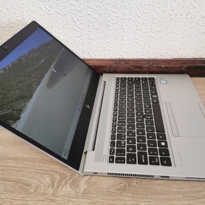 Computador portátil HP EliteBook prateado com teclado preto em fundo de madeira.