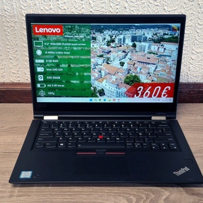 Portátil preto Lenovo numa mesa de madeira clara com informação técnica e preço no ecrã