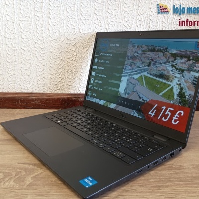 Portátil Dell preto aberto sobre mesa de madeira com ecrã ligado e preço visível