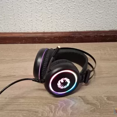 Headset preto com luzes LED multicoloridas colocado no chão de madeira