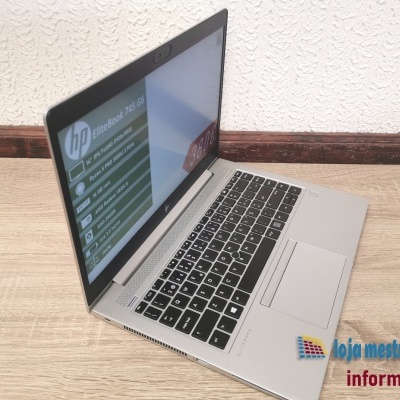 Portátil HP EliteBook prateado aberto sobre chão de madeira e parede branca