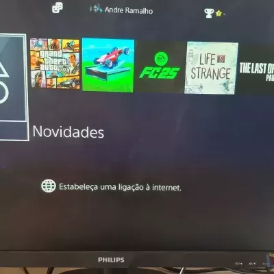 Monitor Philips mostrando menu de PlayStation com ícones de jogos e texto em português