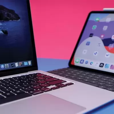 Computador portátil prateado e tablet com teclado em fundo rosa