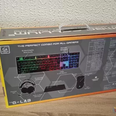 Caixa de conjunto gaming G-LAB com teclado, rato, auscultadores e tapete de rato em fundo de chão de madeira