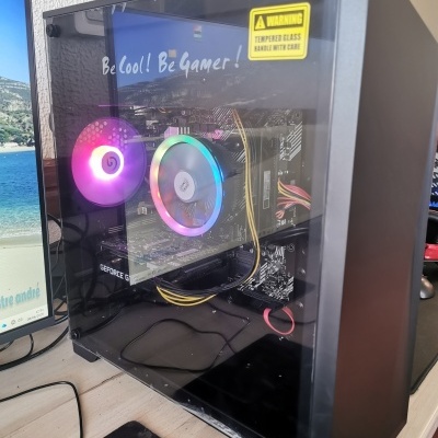 Computador de secretária preto com vidro temperado e iluminação RGB visível, com texto de aviso e frases no vidro