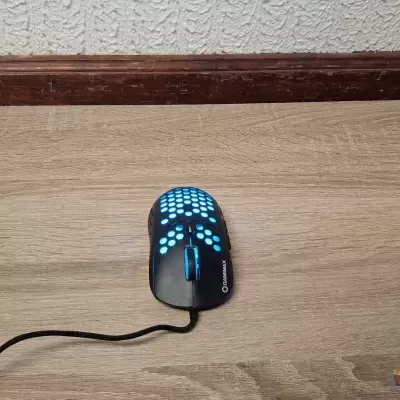 Rato de computador iluminado a azul no chão de madeira